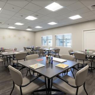 A well-lit classroom setup with tables and chairs, featuring documents on the tables.