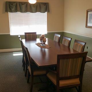 A neatly arranged dining room with a long wooden table and several chairs around it, situated by a window.