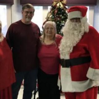 A group poses with Santa Claus in a festive setting.