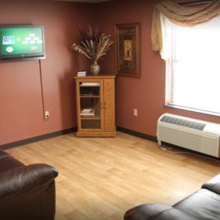 A cozy living room with a wall-mounted television, cabinet, and sofa on a wooden floor.