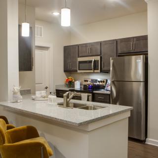 A modern kitchen with stainless steel appliances and elegant pendant lighting.