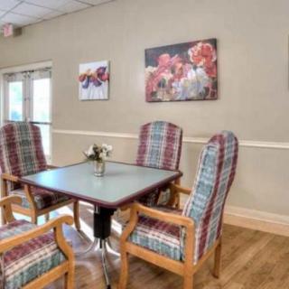 A cozy dining area with a table and four plaid-upholstered chairs, adorned with floral artwork on the walls.