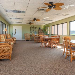 A spacious indoor seating area with wicker furniture and large windows letting in natural light.