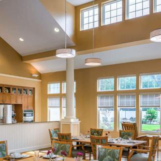 A well-lit dining area with tables and chairs, enhanced by large windows allowing natural light to fill the space.