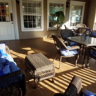 A cozy outdoor patio area with comfortable seating and a table, bathed in warm sunlight.