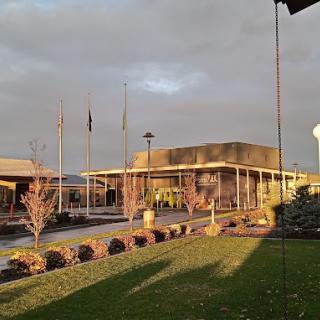 A building at sunset with flags and trees in the foreground under a cloudy sky.