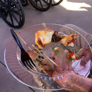 A plate with appetizers and a black fork during an outdoor event.