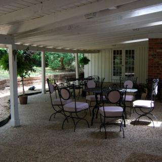 A quiet patio with outdoor seating under a covered area, surrounded by greenery.