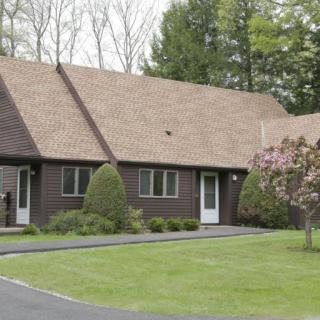 A suburban house with a well-maintained lawn and surrounding trees.