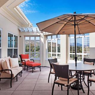 A sunny patio featuring outdoor furniture with an umbrella, offering a scenic view.