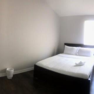 A minimalist bedroom with a neatly made bed and natural light from the window.