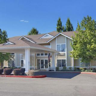 A two-story residential building with a front entrance and surrounding trees.