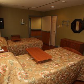 A cozy hotel room with two beds and simple furnishings.