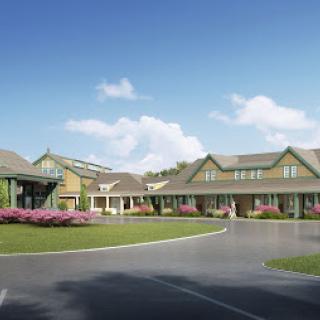 A beautifully designed residential building surrounded by vibrant flowers and a clear blue sky.