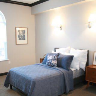 A cozy bedroom with a neatly made bed, bedside tables, and wall-mounted lamps.