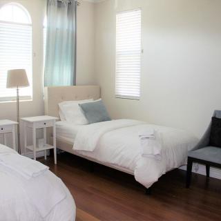A minimalist bedroom with two twin beds, white bedding, and a wooden floor.