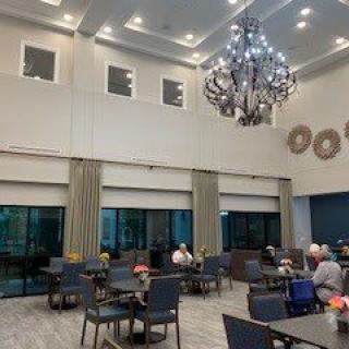 A spacious dining area with a large chandelier, where people are seated at tables.