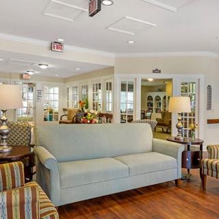 A cozy living room interior with a sofa, striped armchairs, and table lamps on wooden flooring.