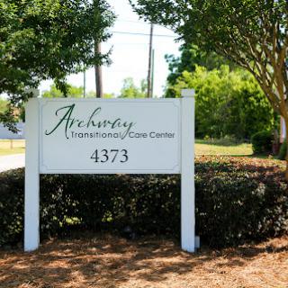 Sign for a business location surrounded by greenery.