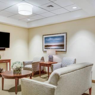 A cozy waiting room with comfortable seating, a television, and wall art.