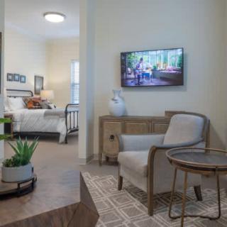 A cozy living room with a view into an adjacent bedroom, featuring modern furniture and decor.