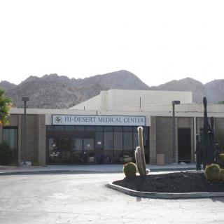 The exterior of a museum with sculptures in the foreground, set against a mountainous desert backdrop.