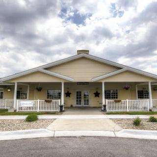 A single-story building with a large porch and cloudy sky overhead.