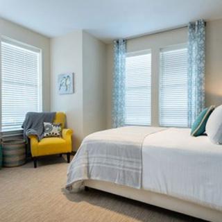 A cozy bedroom with a comfortable bed and a yellow armchair near the window.