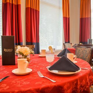An elegantly set dining table with a red tablecloth and black napkins in a restaurant.
