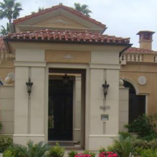 A Mediterranean-style building entrance with columns and surrounding palm trees.
