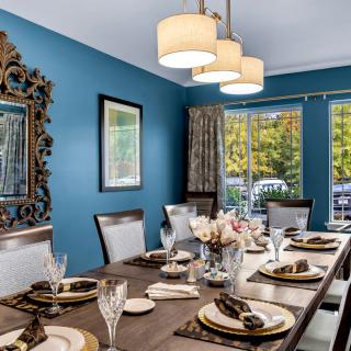 An elegantly decorated dining room with blue walls, featuring a large dining table set for a meal.