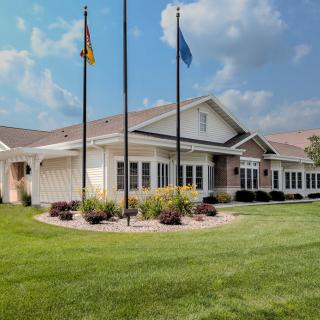A well-maintained building with flags in front, surrounded by a neatly manicured lawn and landscaping under a partly cloudy sky.