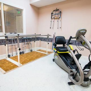 Indoor gym facility featuring a recumbent bike and parallel bars for exercise and rehabilitation.