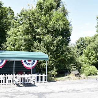 A peaceful outdoor scene featuring a canopy adorned with red, white, and blue decorations surrounded by lush greenery.