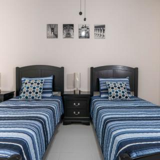 A neatly arranged bedroom with two twin beds featuring striped bedding, complemented by a central nightstand and decorative wall art.