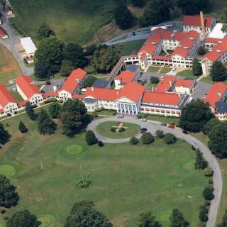 An aerial view of a complex with red roofs surrounded by greenery.