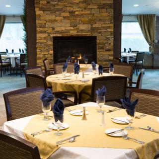A cozy restaurant dining area with elegantly set tables and a warm fireplace.