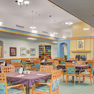 A spacious dining room with neatly arranged tables and chairs, featuring warm lighting and decorative elements.