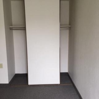 An empty minimalist closet with a sliding door and hanging rod.