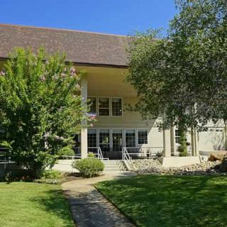 A beautiful house with a lush garden and spacious lawn under a clear blue sky.