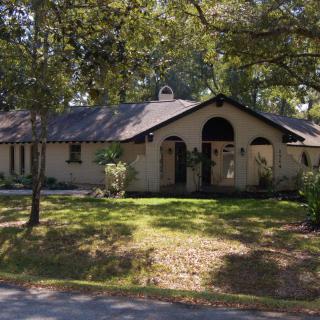 A suburban house with a spacious front yard and surrounding trees.