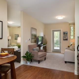 A cozy living room with a dining area, featuring modern furniture and natural lighting.