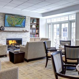 A cozy living room featuring a fireplace, comfortable seating, a wall-mounted television, and large windows.