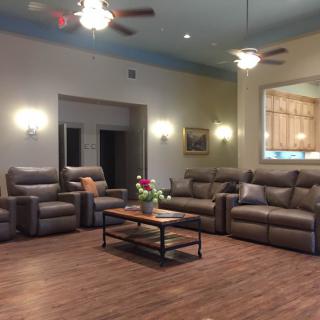 Spacious living room with comfortable leather sofas, warm wood flooring, and elegant lighting.