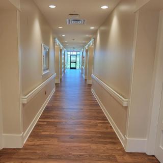 A long, bright hallway with wooden flooring and overhead lighting.