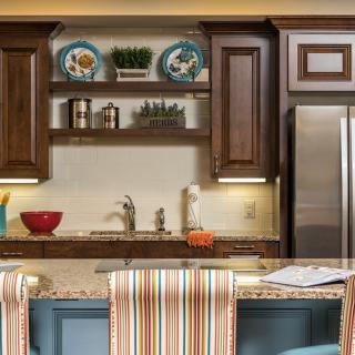 A cozy kitchen with wooden cabinets, decorative plates, and a modern stainless steel refrigerator.