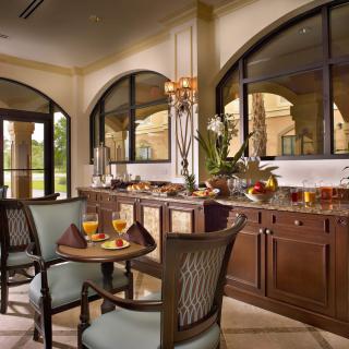 A luxurious dining room with a buffet spread, elegant furniture, and large windows.
