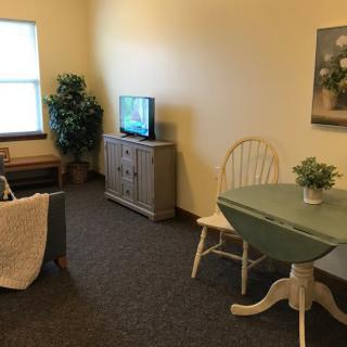 A cozy living room with a TV, a small dining table, and comfortable seating.