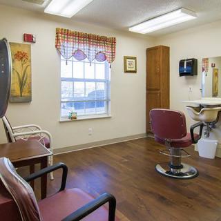 A cozy salon room with a barber chair, mirror, and seating area.