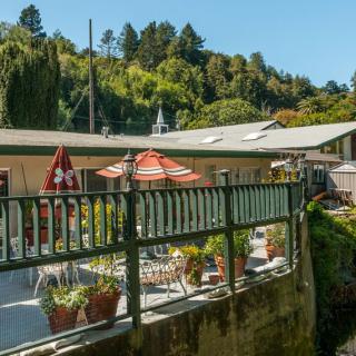 A cozy outdoor patio with tables and umbrellas, surrounded by lush greenery.